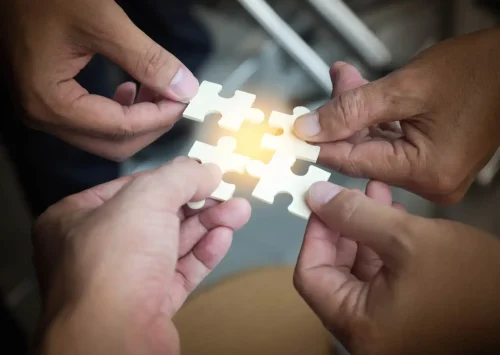 Group of business people assembling jigsaw puzzle wanting to put pieces of puzzle together on wood table backgroung for help support, teamwork concept